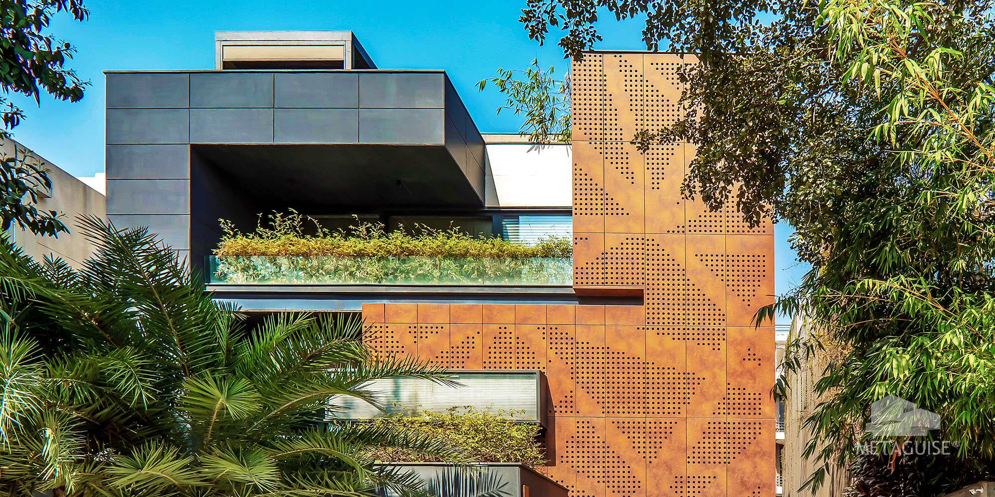 Perforated corten steel screen beside a planted terrace on a residential elevation