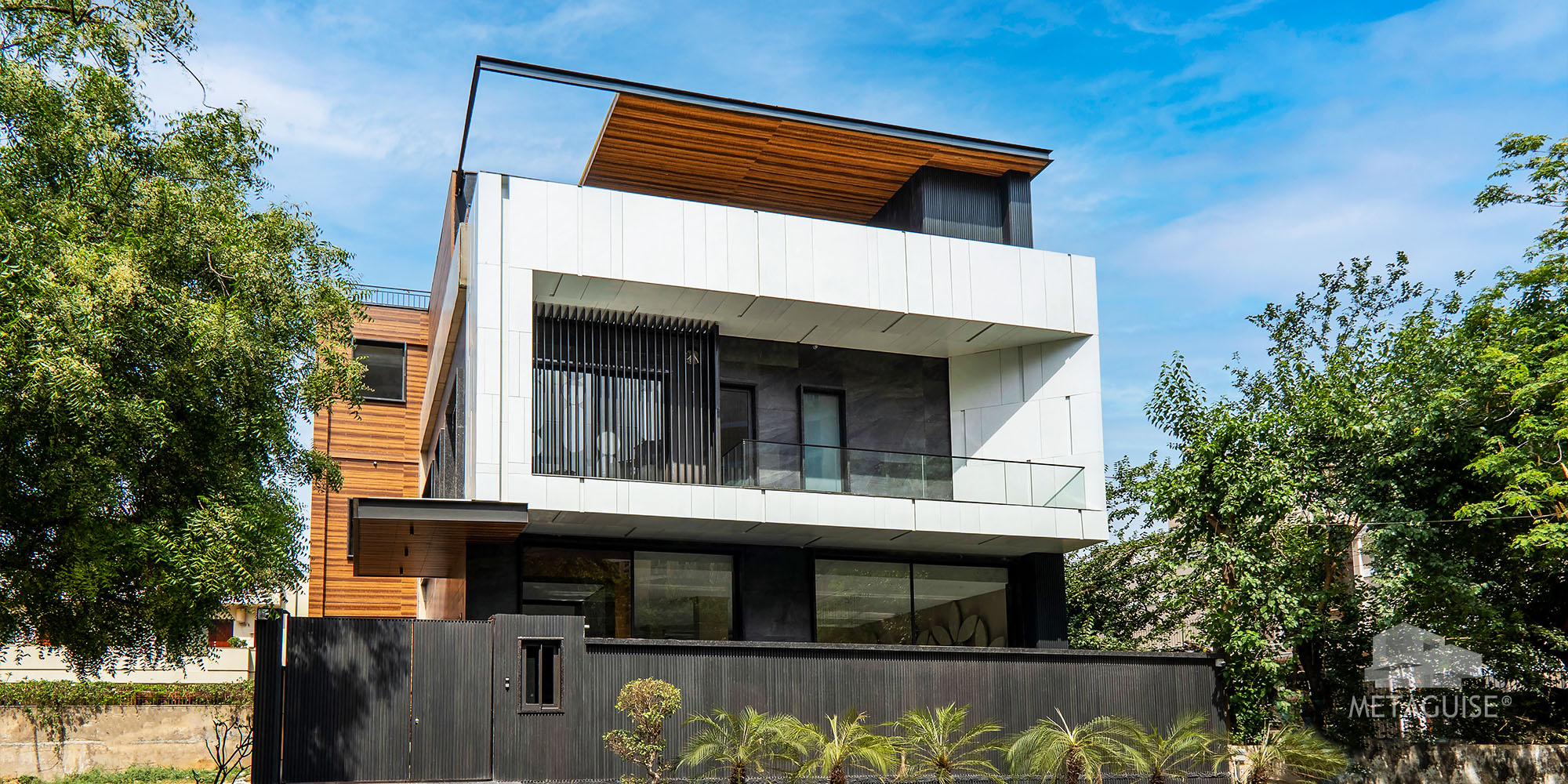 Modern residence with white and dark cladding, a glass balcony and landscaped frontage