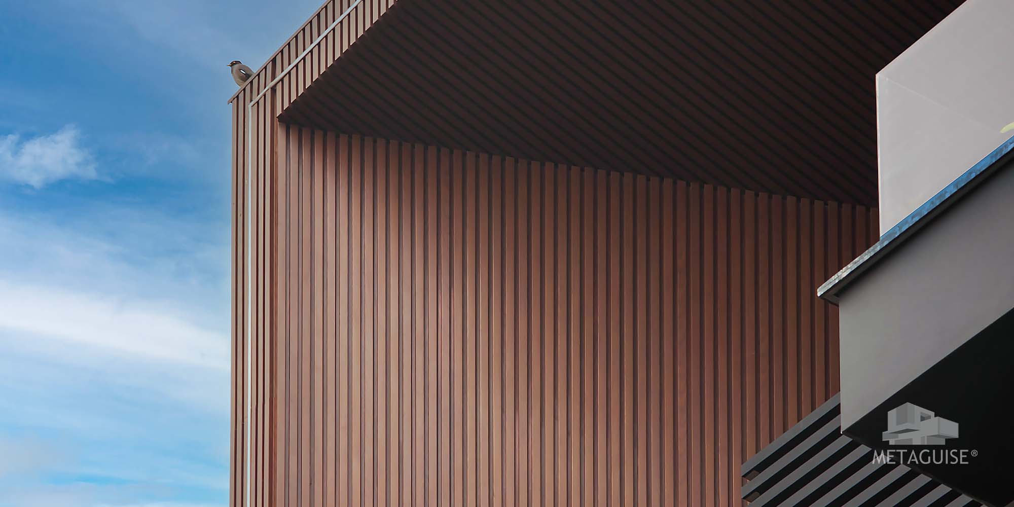 Material zoning with stone base and metal cladding on front elevation - Metaguise