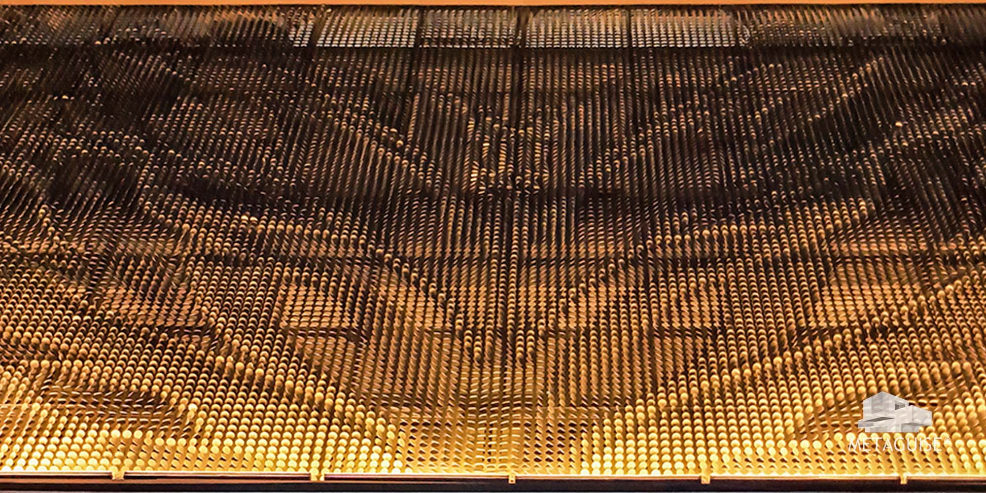 Close-up of a dense field of gold metal discs forming a large image on a facade panel