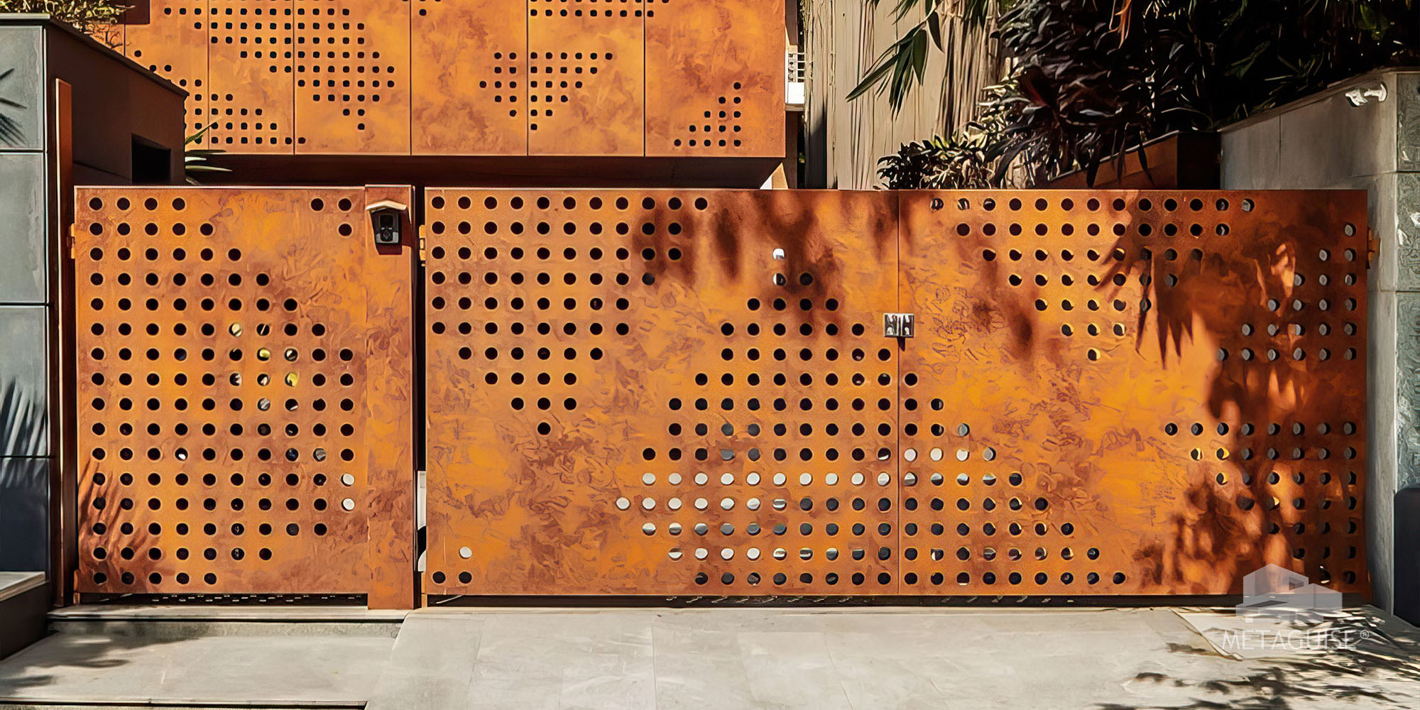 Perforated corten steel gate and wall panel on a residence catching dappled sunlight