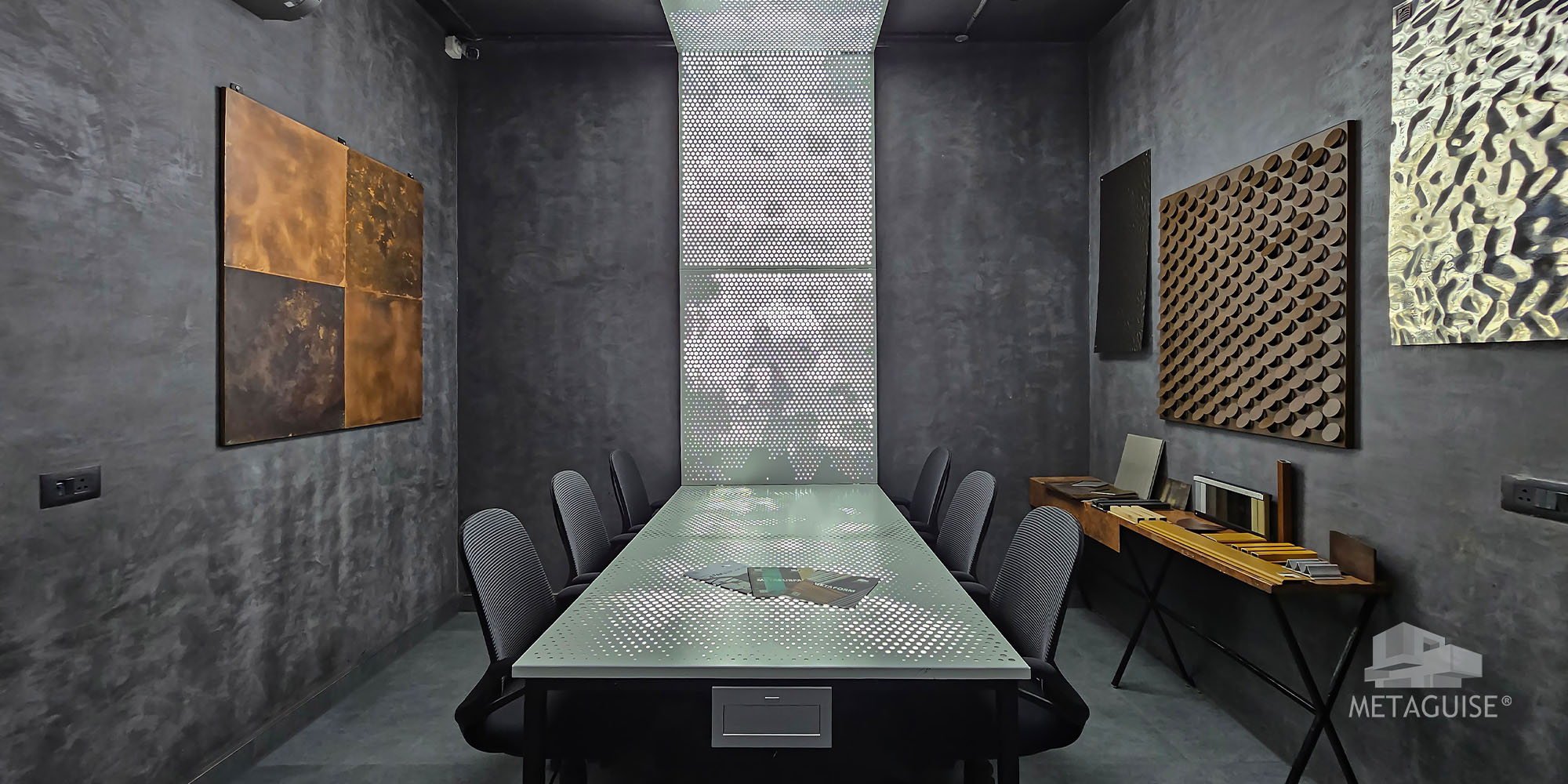 Meeting room at Metaland Gurugram with metal facade finish samples mounted on dark walls above a glass-top table